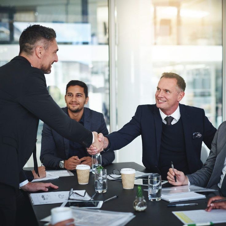 Two professionals shaking hands across a meeting table